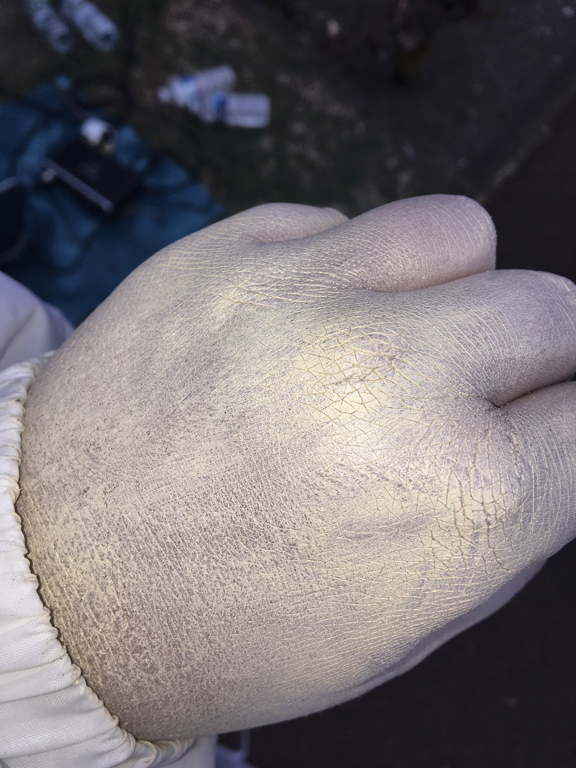 Une main est recourte de maquillage blanc au reflets dorés.